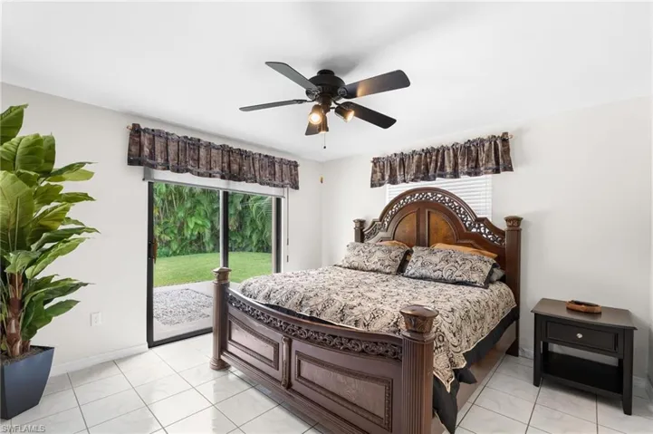 White tile flooring, ceiling fan with integrated lighting, and sliding glass doors opening to outdoor space