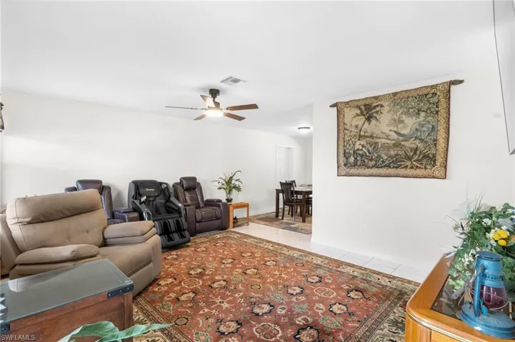 White walls, ceiling fan with light fixture, and tile flooring