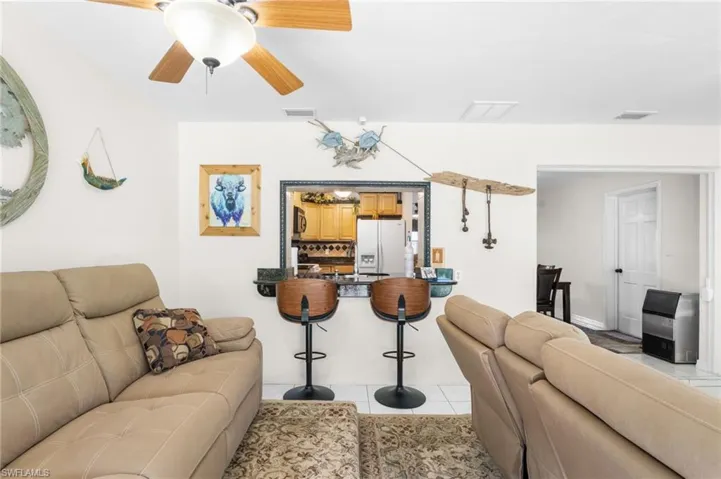 Open concept living space featuring a ceiling fan, recessed lighting, and a pass-through window to the kitchen
