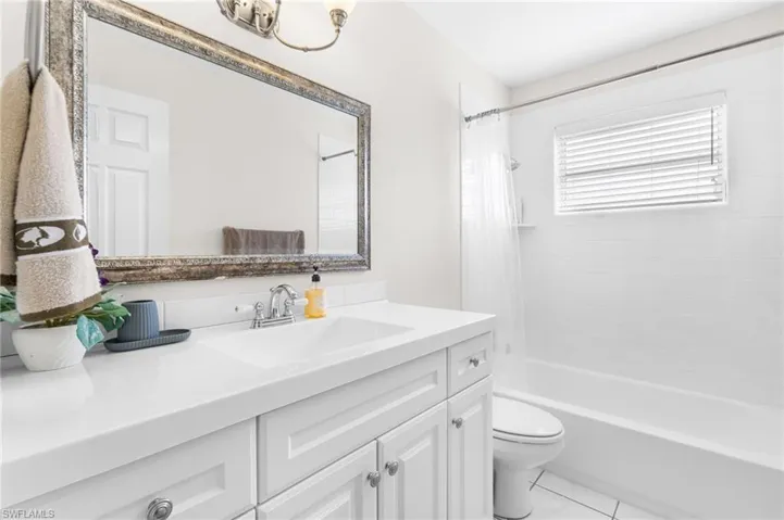 White vanity with integrated sink, chrome faucet, and decorative framed mirror