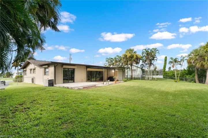 Expansive rear lawn featuring a paved patio and multiple sliding glass doors