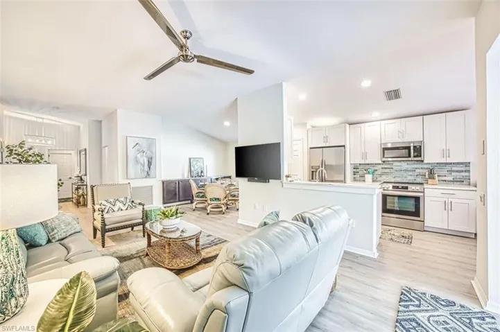 Living area with ceiling fan, light wood-type flooring, lofted ceiling, and recessed lighting