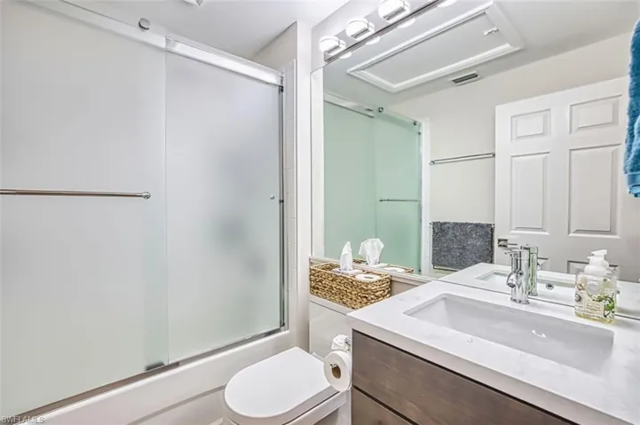 Full bathroom with vanity and enclosed tub / shower combo