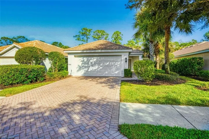 View of front facade featuring decorative driveway, an attached garage, stucco siding, and a tiled roof