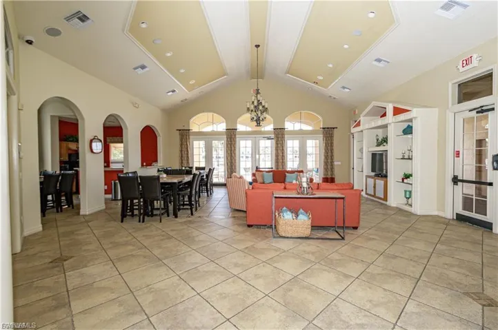 Living room featuring french doors, arched walkways, light tile patterned floors, a chandelier, and a high ceiling