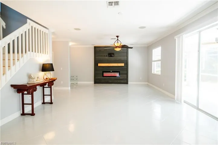 Living area with ornamental molding, a fireplace, and light tile patterned flooring