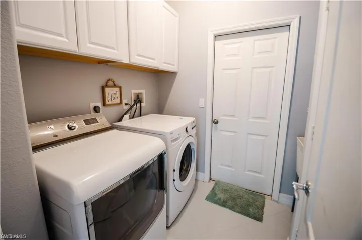 Laundry room with cabinet space, washing machine and dryer, and light tile patterned floors