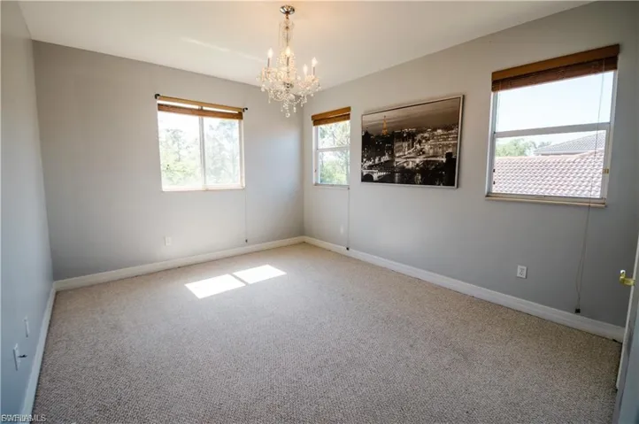 Carpeted spare room with suspended lighting and healthy amount of natural light