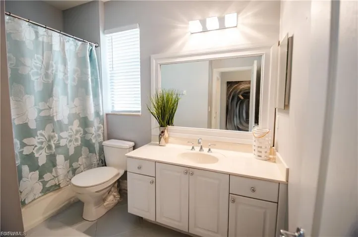 Bathroom featuring vanity, tile patterned flooring, and shower / bath combination with curtain