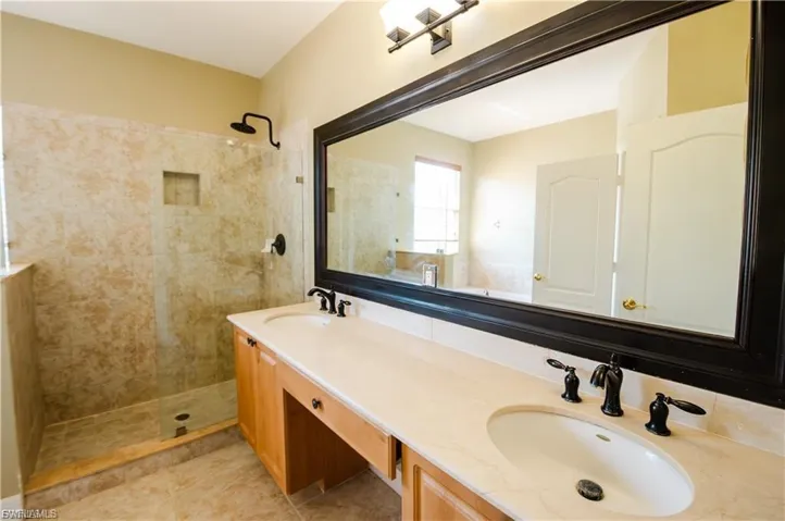 Bathroom featuring double vanity and tiled shower