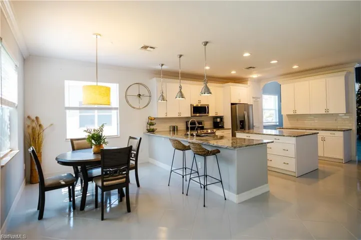 Kitchen with a peninsula, pendant lighting, backsplash, white cabinets, and crown molding