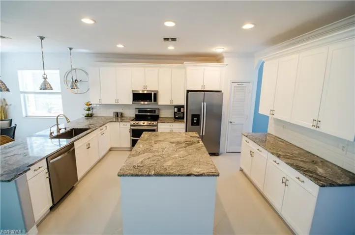 Kitchen featuring dark stone countertops, a peninsula, stainless steel appliances, and ornamental molding