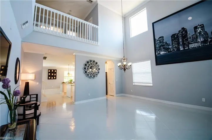 Living room with crown molding, a high ceiling, healthy amount of natural light, arched walkways, and light tile patterned flooring