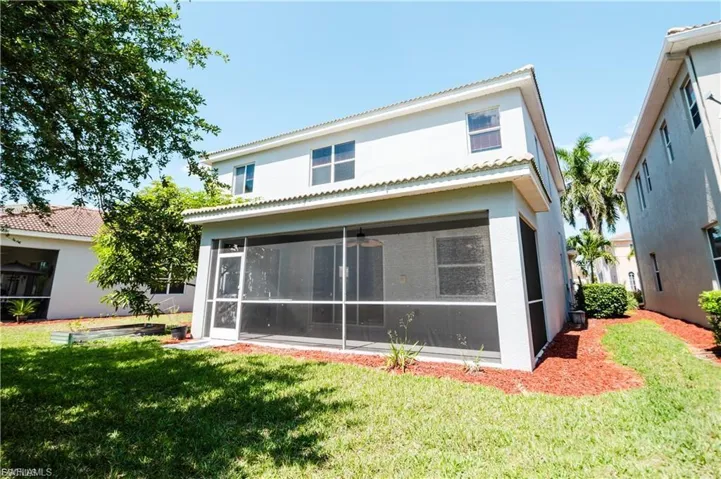 Rear view of property featuring stucco siding, a lawn, a tile roof, and a sunroom