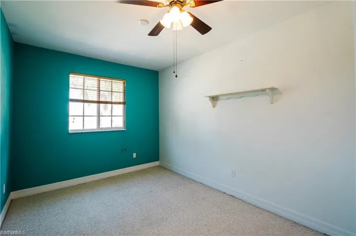 Carpeted spare room with ceiling fan and baseboards