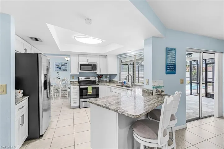 Newer kitchen with stone counters and breakfast bar and newer appliances and pass thru window