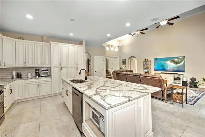 Kitchen with white cabinetry, sink, dishwasher, and a kitchen island with sink