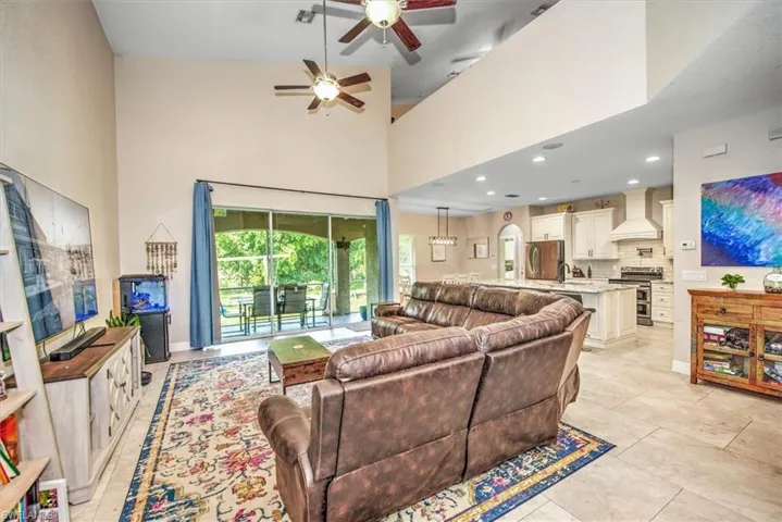 Living room with ceiling fan, light tile patterned floors, and a high ceiling