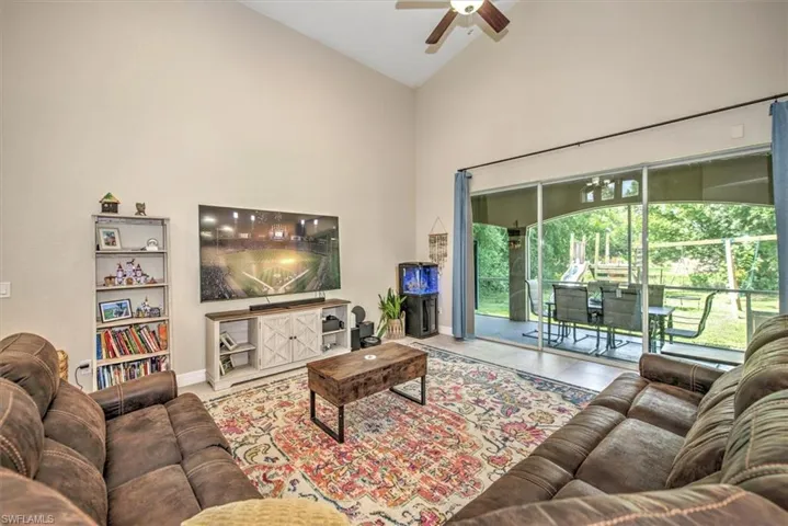 Living room with tile patterned flooring, high vaulted ceiling, and ceiling fan