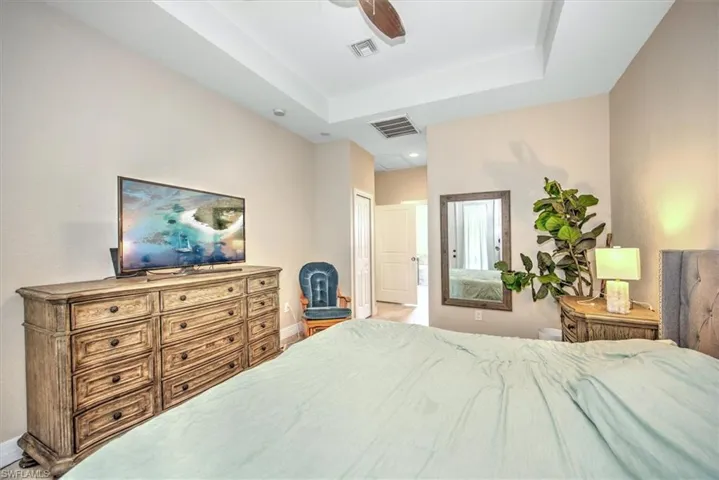 Bedroom with ceiling fan, a closet, and a tray ceiling