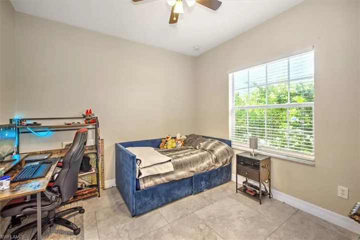 Tiled bedroom featuring ceiling fan