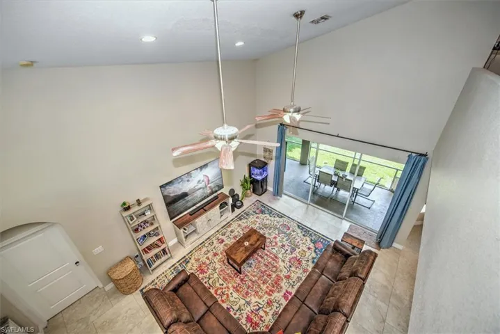 Living room with ceiling fan, high vaulted ceiling, and light tile patterned flooring