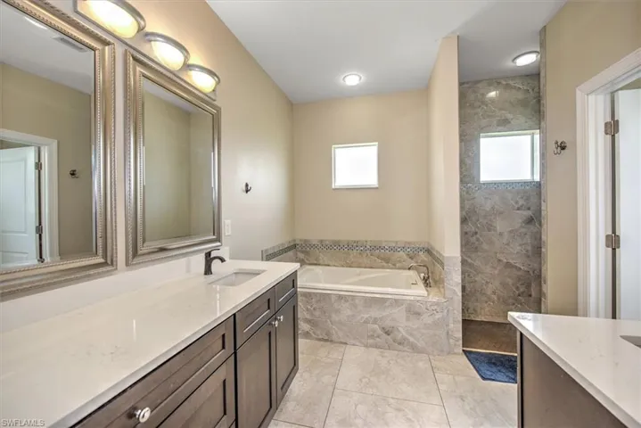 Bathroom with vanity, tile patterned floors, a wealth of natural light, and independent shower and bath
