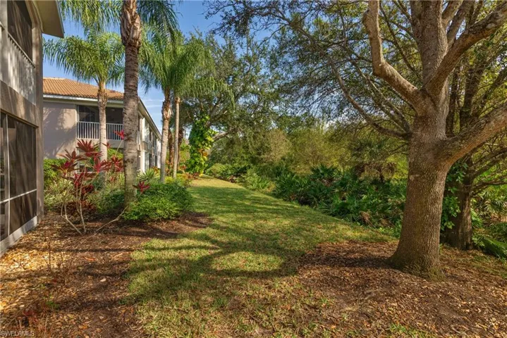 View of grassy yard featuring a balcony