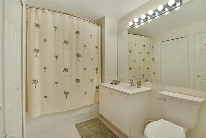 Bathroom with vanity, shower / bath combo, and light tile patterned flooring