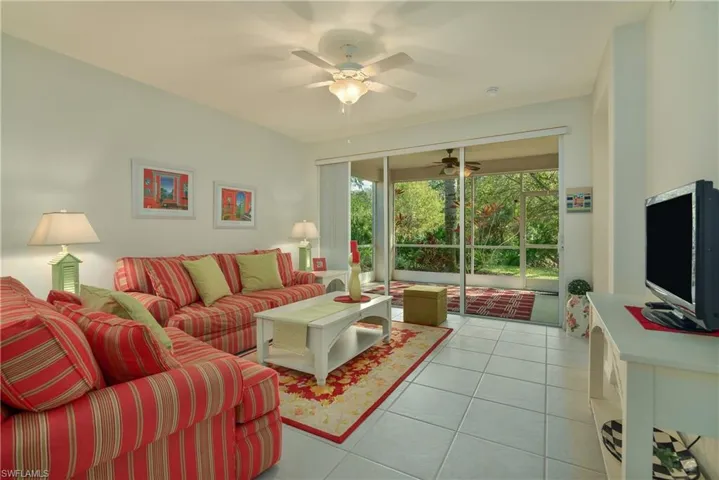 Living room featuring light tile patterned floors, a ceiling fan, and a sunroom