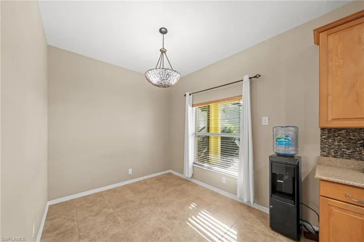 Unfurnished dining area with light tile patterned floors and baseboards