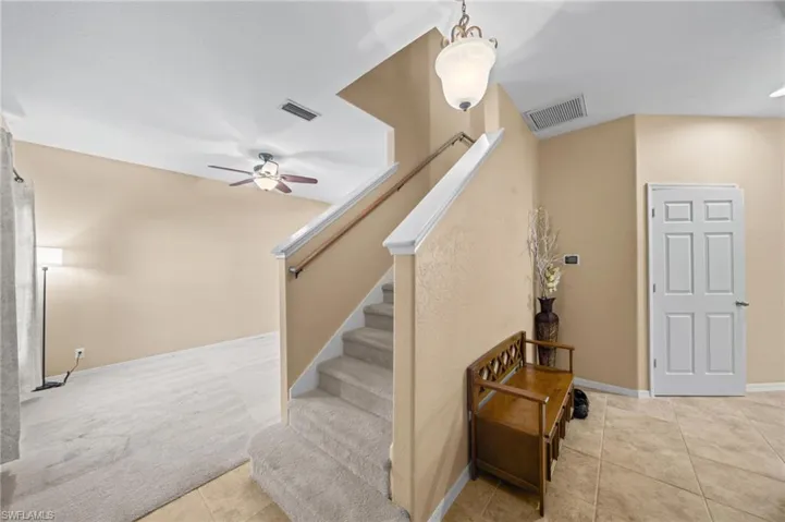 Stairway featuring tile patterned floors, carpet floors, and ceiling fan