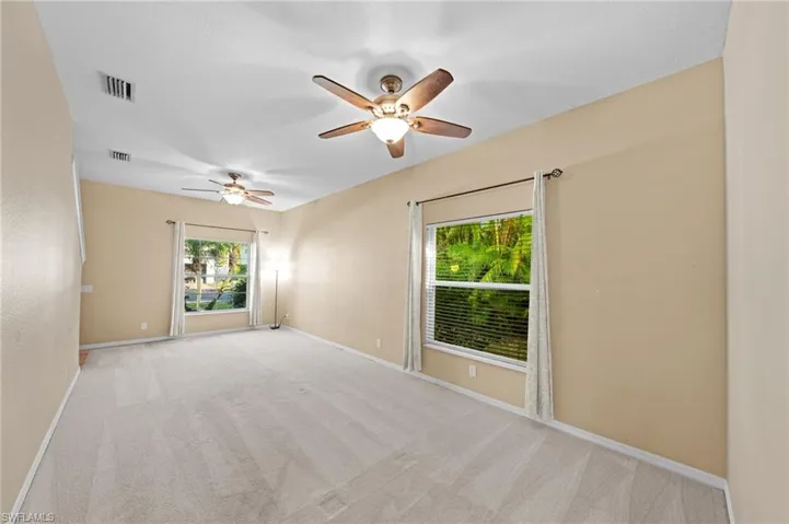 Carpeted spare room with baseboards and ceiling fan