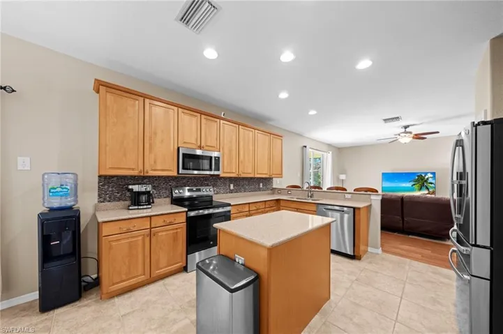Kitchen featuring a peninsula, stainless steel appliances, open floor plan, light stone countertops, and recessed lighting