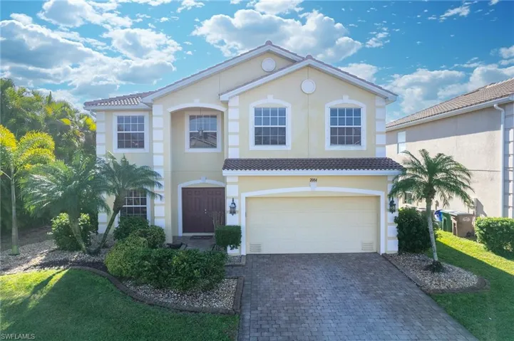 Mediterranean / spanish-style home with an attached garage, stucco siding, decorative driveway, and a front yard