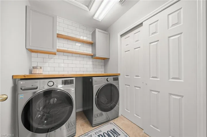 Washroom featuring washer and clothes dryer, cabinet space, and light tile patterned floors
