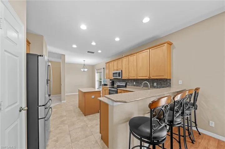 Kitchen with a center island, a breakfast bar area, appliances with stainless steel finishes, a peninsula, and recessed lighting