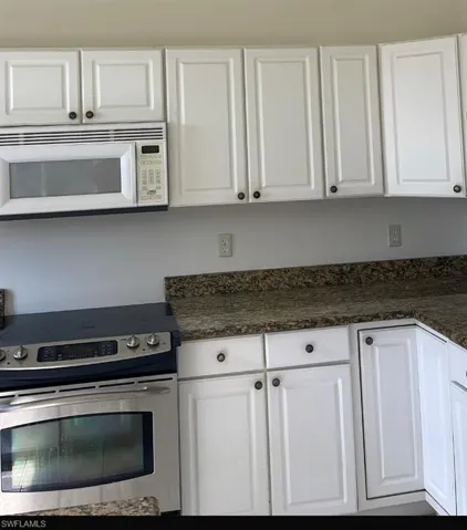 Kitchen with stainless steel electric range and white cabinets