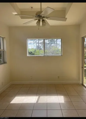 Tiled spare room featuring ceiling fan