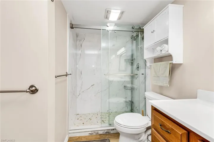 Bathroom featuring vanity and a marble finish shower