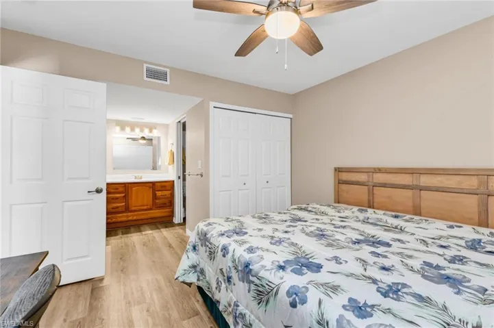 Bedroom with light wood-style floors, a closet, ceiling fan, and connected bathroom