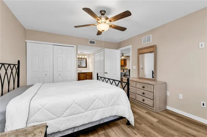 Bedroom with multiple closets, light wood-style flooring, and a ceiling fan