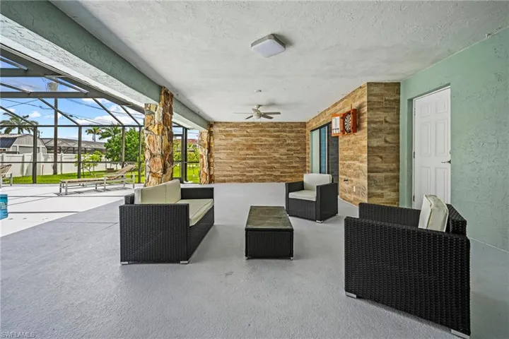 Expansive screened patio featuring stone accent walls, a ceiling fan, and recessed lighting