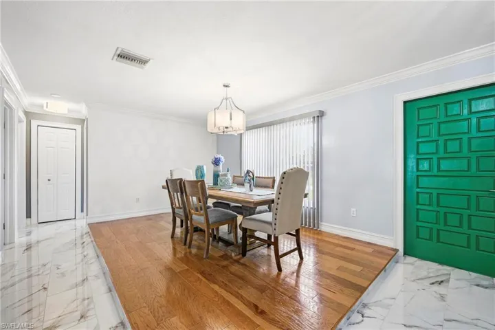 Dining area featuring a contemporary chandelier, hardwood flooring, and a large window with vertical blinds