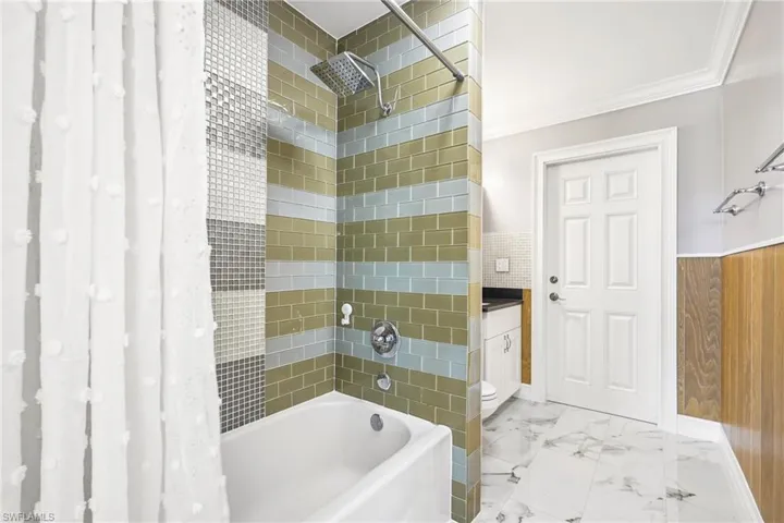Bathroom featuring a combined tub and shower with a rainfall showerhead, subway tile surround, and mosaic tile accent