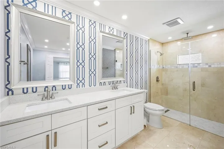 Dual vanity featuring white shaker cabinetry, quartz countertops, and brushed nickel fixtures