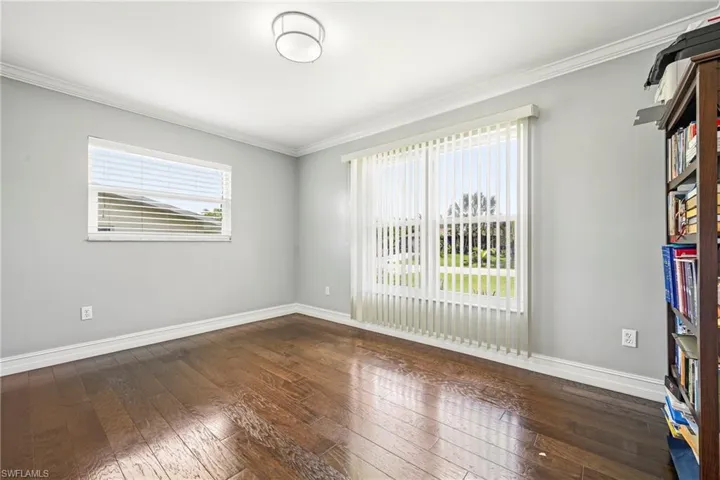 Bright interior space featuring wood-finish flooring, light gray walls, and white crown molding