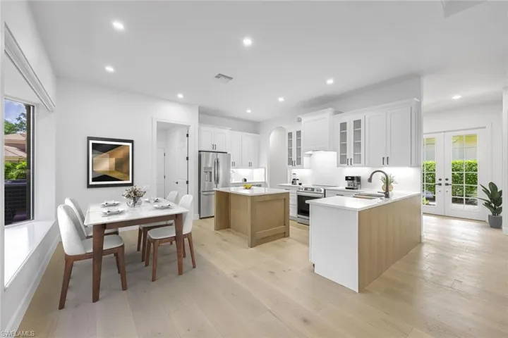 Kitchen with stainless steel refrigerator with ice dispenser, arched walkways, a center island, light wood-type flooring, and french doors