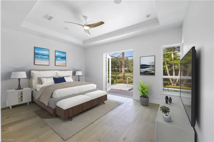 Staged Primary Bedroom featuring a tray ceiling, access to outside, light wood-style floors, a ceiling fan, and ornamental molding