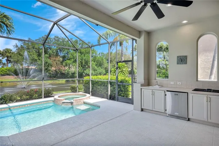 View of swimming pool featuring area for grilling, a ceiling fan, a patio, glass enclosure, and a pool with connected hot tub